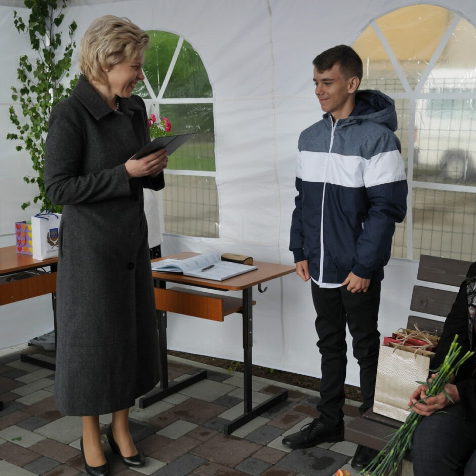 Direktore pasniedz atestātu absolventam 2021. gada izlaidumā