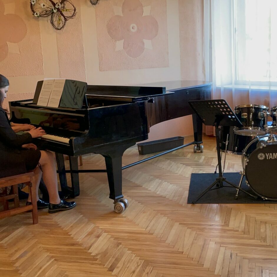 Audzēkņu vakarā audzēkne ar skolotāju spēlē klavieru ansambli