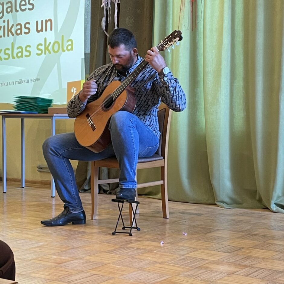 Skolotājs Lauris Krasņikovs spēlē ģitāru 20222./2023.m.g. atklāšanas pasākumā
