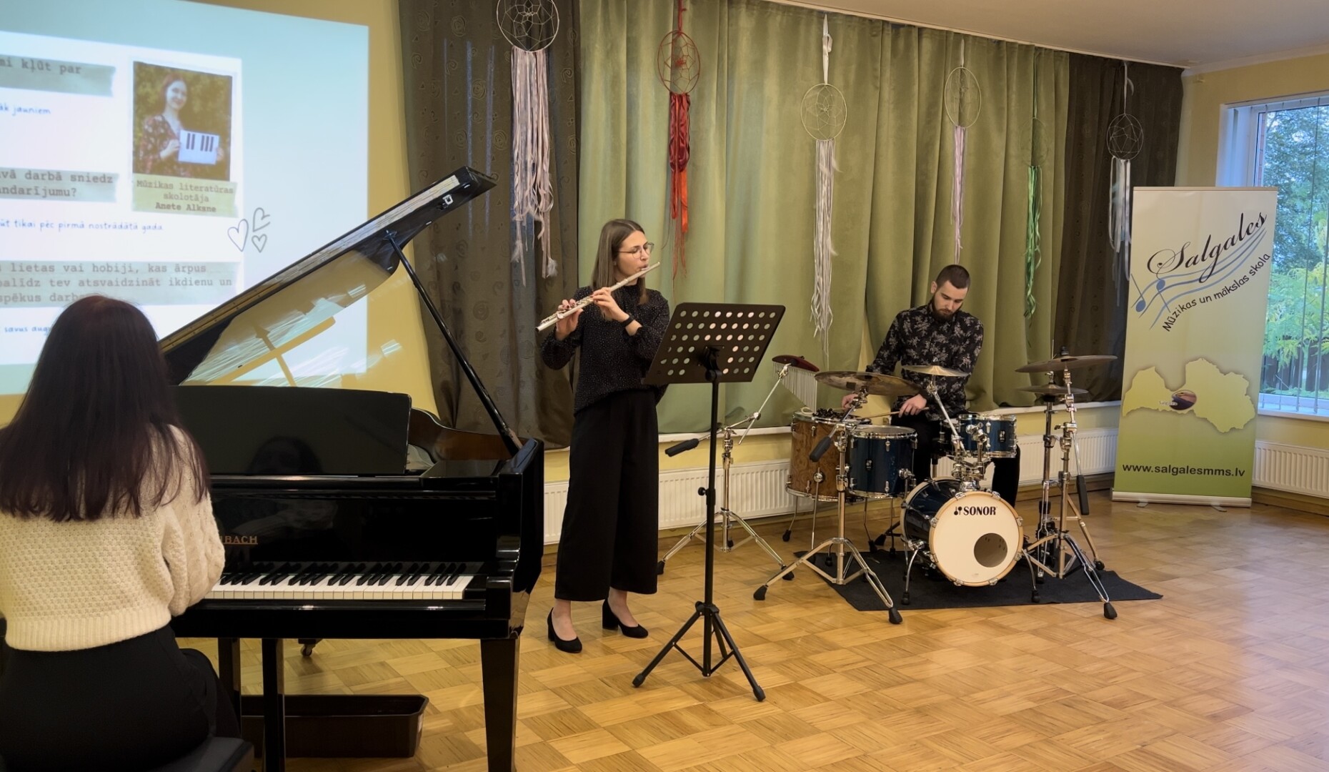 Skolotāju dienas koncertā uzstājas skolotāji - Mareks Alksnis (sitaminstrumenti), Lita Gārbena (flauta), Anete Alksne (klavieres, vokāls)