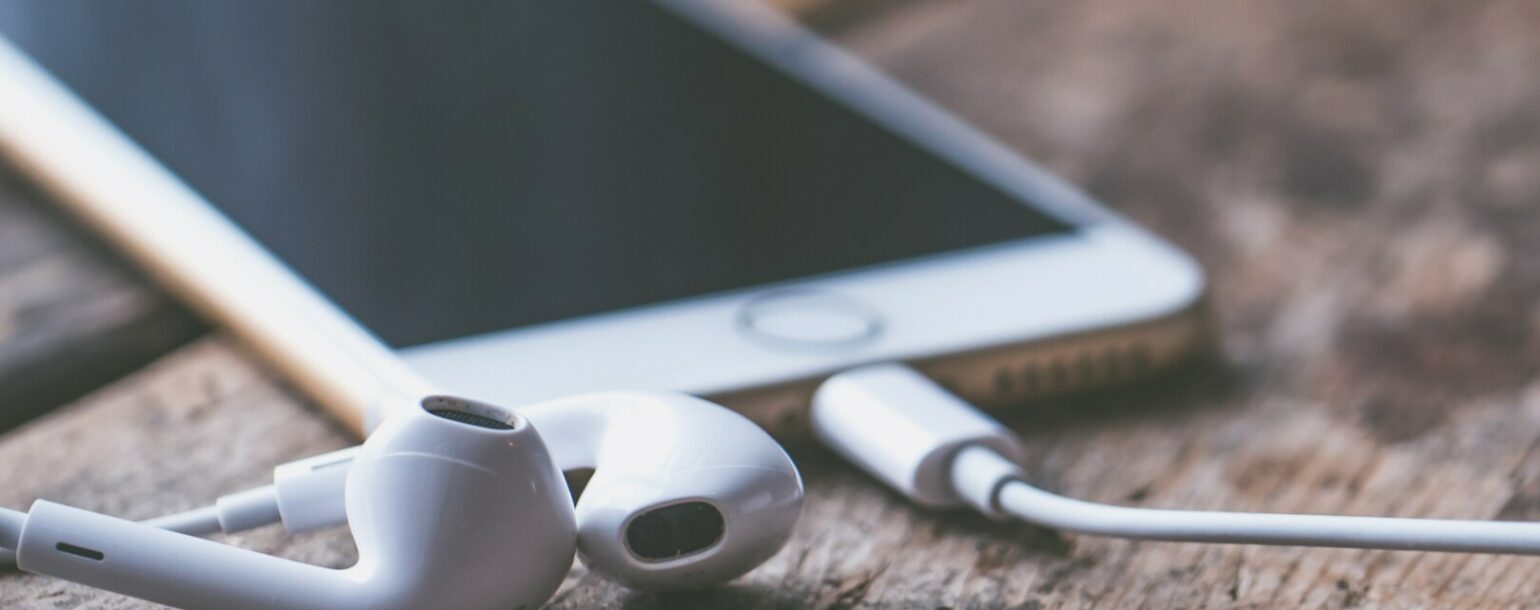 Austiņas un iPhone telefons uz galda