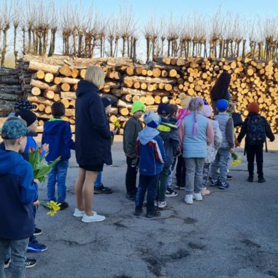 Atvērto durvju dienas dalībnieki ārā pie mākslas skolas, klausās mākslas skolotājā