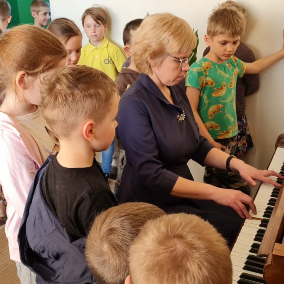 Atvērto durvju dienas dalībnieki Kamerzālē pie klavierēm, kopā ar direktori