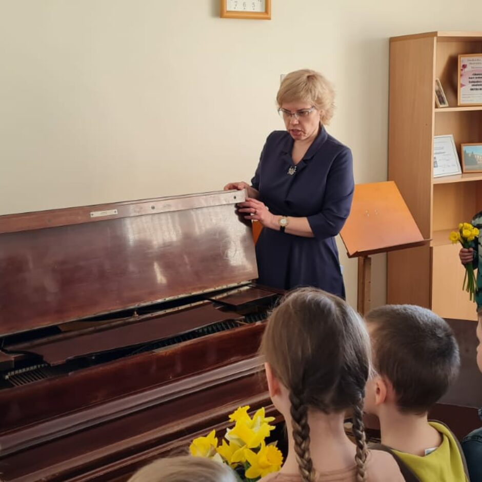 Atvērto durvju dienas dalībnieki Kamerzālē pie klavierēm, kopā ar direktori