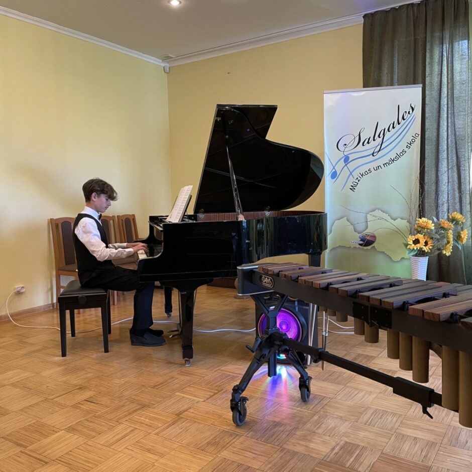Sitaminstrumentu spēles audzēknis spēlē klavieres koncertā