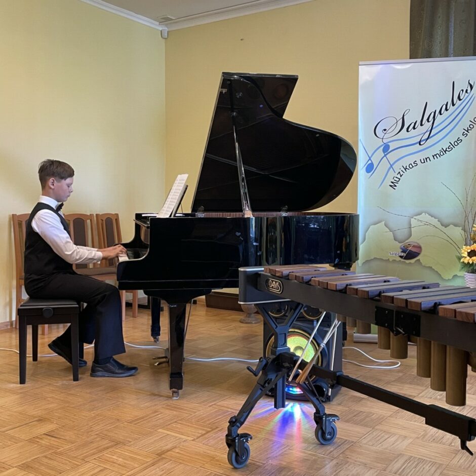 Sitaminstrumentu spēles audzēknis spēlē klavieres koncertā