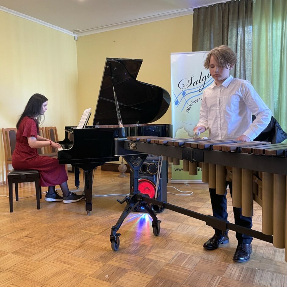 Sitaminstrumentu spēles audzēknis spēlē marimbu koncertā ar koncertmeistari