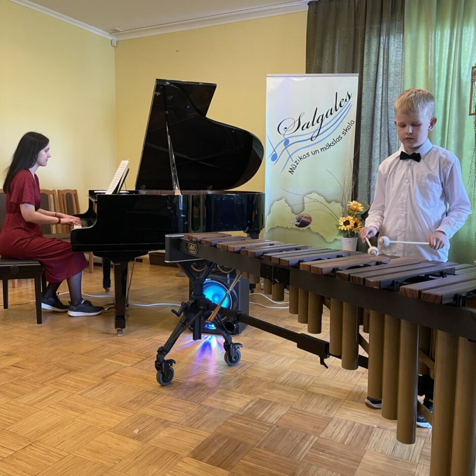 Sitaminstrumentu spēles audzēknis spēlē marimbu koncertā ar koncertmeistari