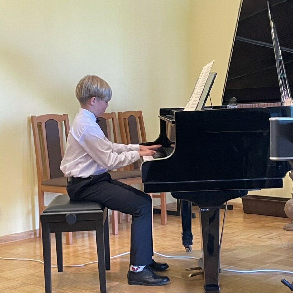 Sitaminstrumentu spēles audzēknis spēlē klavieres koncertā