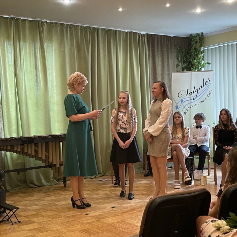 Direktore sveic skolas vizuāli plastiskās mākslas programmas absolventi un viņa vecomāti izlaidumā