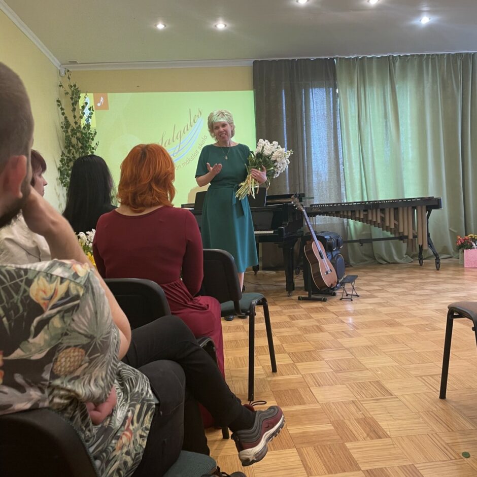 Direktore sveic pedagogus, dāvinot ziedus izlaidumā