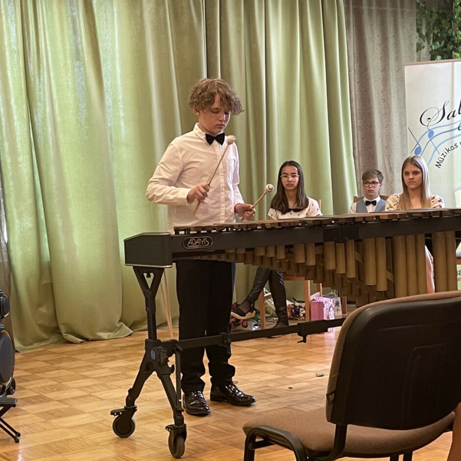 Sitaminstrumentu spēles absolvents spēlē marimbu izlaidumā