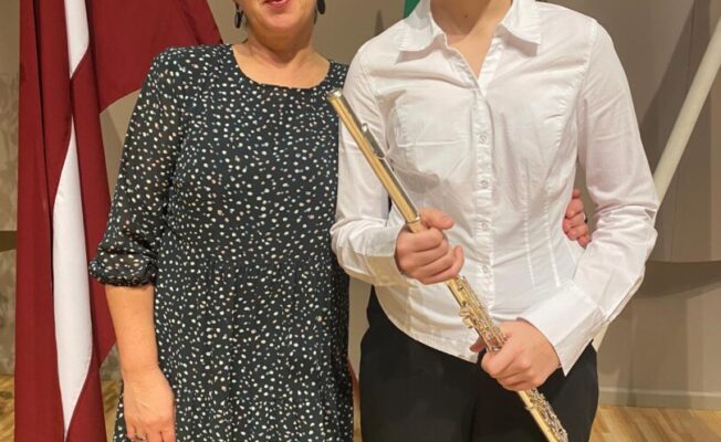 Jauna sieviete smaidot tur galda spēli ar vāku, uz kura redzams teksts 