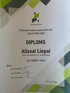 Smaidīga jauna sieviete bežīgā džemperī. Viņa kreisajā rokā tur galda spēles kasti "Flow", uz kuras attēloti dzīvnieki ar pilsētas panorāmu fonā, un labajā rokā tur diplomu. Diploms no Saldus Mūzikas skolas apliecina Alisas Liepas iegūto I vietu Pūšaminstrumentu spēles konkursā "BALTU PUTNI 2023".
