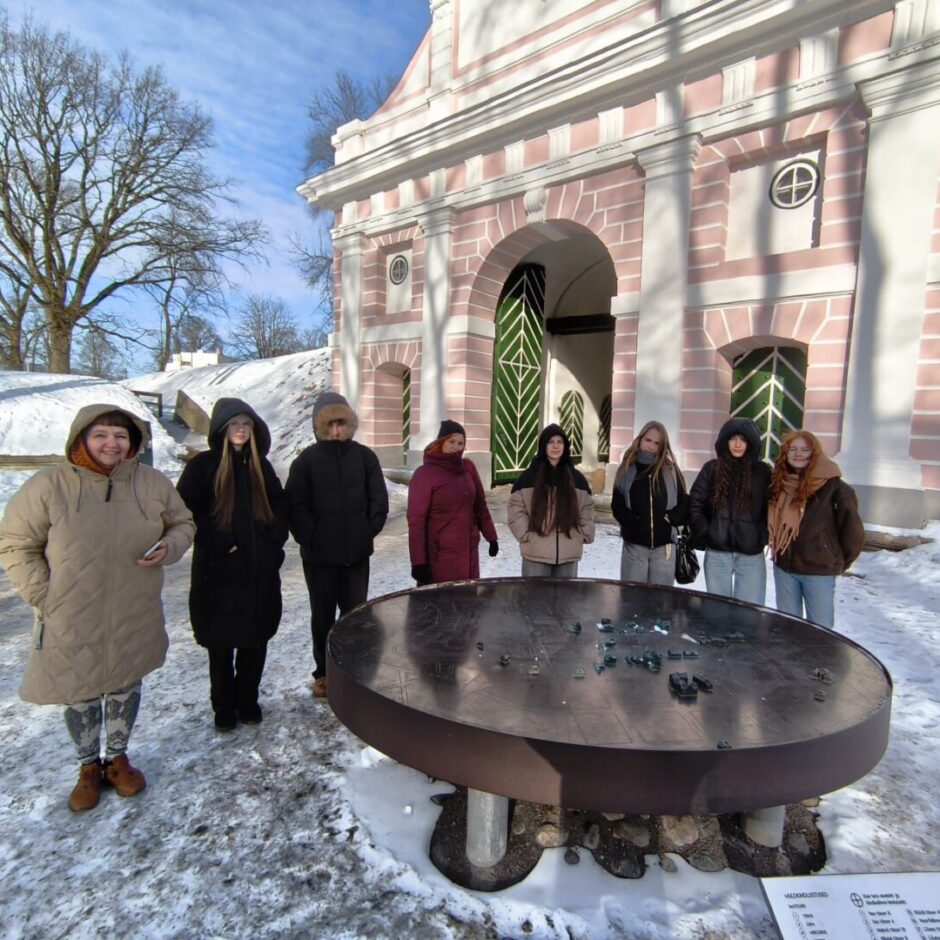 Cilvēki sēž pie mākslas darba.